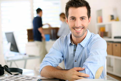 Smiling man with arms crossed in office