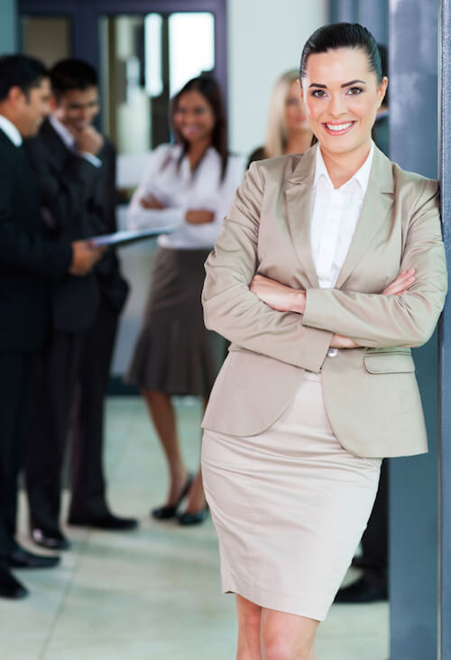 businesswoman standing in office with colleagues on background